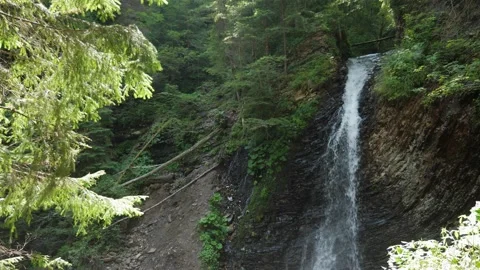 Alive waterfall with a dabbling flow on a steep stone and grass hill on a sunny Stock-Footage 165040069
