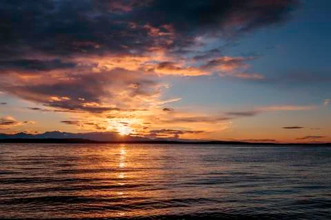 Alki Beach Sunset with Olympic Range Silhouetted and Water Reflections. Stock Photos
