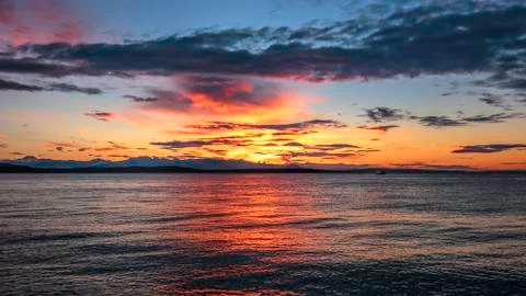 Alki Beach Sunset with Olympic Range Silhouetted and Water Reflections. . Stock Photos