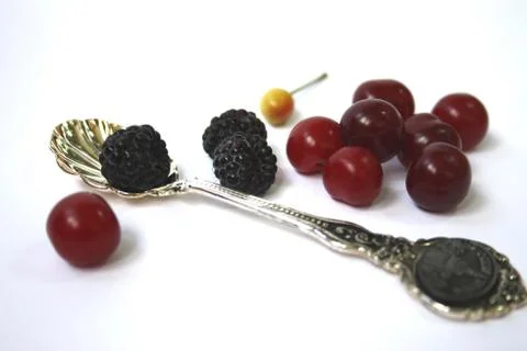 All for a dessert: a cherry, a black raspberry and a spoon Stock Photos