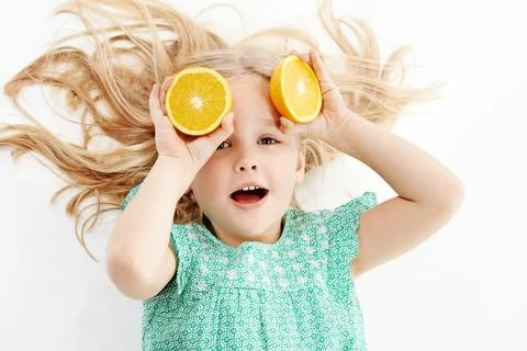 All kinds of citrusy fun. Studio shot of a cute little girl playfully covering Stock Photos