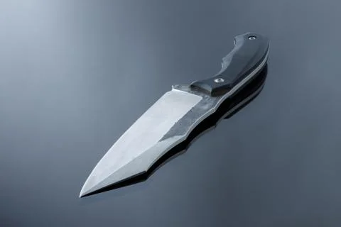 All-metal, tactical, kitchen knife on a mirror surface, handwork, steel blade Stock Photos