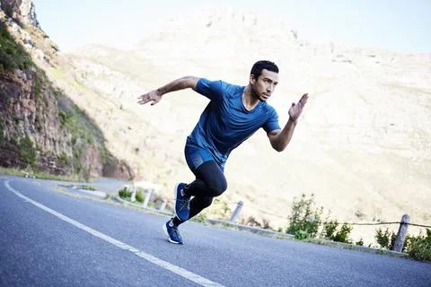 All out pace. Full length shot of a handsome young male athlete out for a run on Stock Photos
