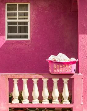 All pink image of a pink laundry basket on a pink porch with white towels Фото