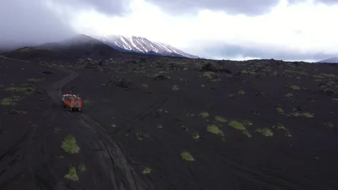 The All-Terrain Vehicle Is Going Through Lava Fields. Video From The Drone. Stock Footage 128772255