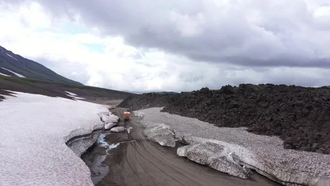 The All-Terrain Vehicle Is Going Through Lava Fields And Glacier. Drone Video. Stock Footage 128772915