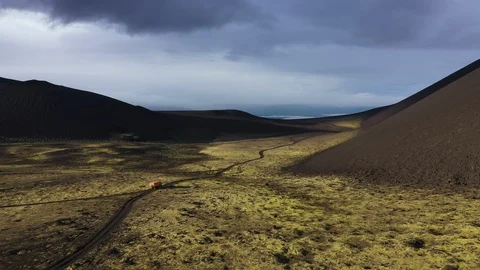 The All-Terrain Vehicle Is Going Through Black Lava Field. Video From The Drone. Stock Footage 128780944