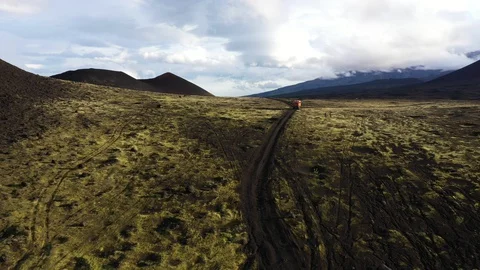 The All-Terrain Vehicle Is Going Through Black Lava Field. Video From The Drone. Stock Footage 128781875