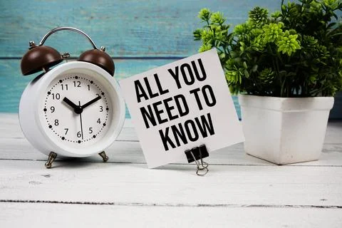 All You Need To Know text written on paper card with alarm clock on wooden .. Foto stock