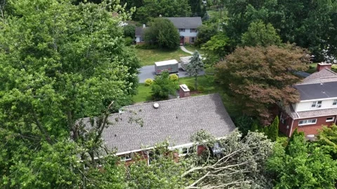 Allen tree branches rest on flat roof section beside brick house in Manheim Stock Footage 341842605