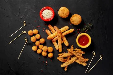 Allsorts of fried snacks with two different sauces on black background. Close-up Stock Photos