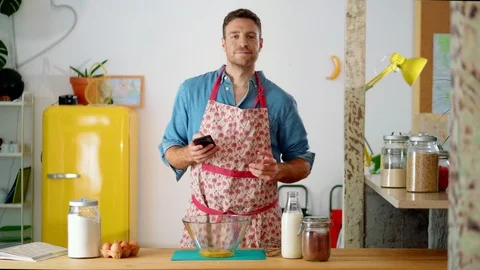 Alluring funny Caucasian guy dancing with black phone in hand while cooking Stock Footage 114916460