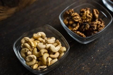 Almond, cachew and walnut in a small plates which standing on a black table Stock Photos