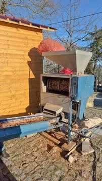 Almond cracking machine with hopper full of nuts and rotating drum visible Stock Photos