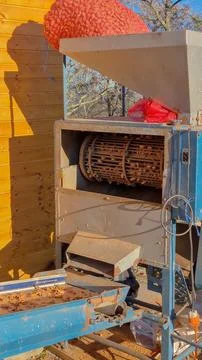 Almond cracking machine with hopper full of nuts and rotating drum visible Stock Photos