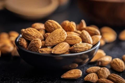 Almond kernel nuts in bowl on black table. Stock Photos