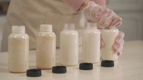 Almond milk making concept. Close-up of woman's hand holding bottle caps and Vídeos de archivo 106204414