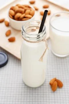 Almond milk with straw in bottle with almonds on table Stock Photos