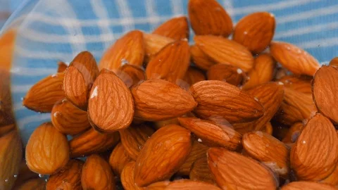 Almond nuts float in water in a glass bowl on the table. Stock Footage 124897399