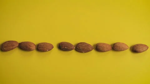 Almond seeds rotating synchronously on yellow background Video stock 171147833