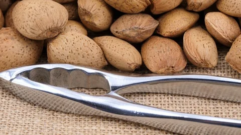 Almonds and nutcracker on jute fabric, tilt down shot Stock Footage 88799659