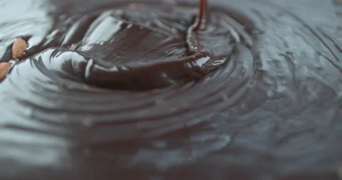 Almonds being thrown into pouring melted chocolate closeup ultra slow motion wit Stock Footage 199460146