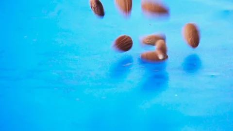 Almonds Dropping On Blue Surface, Slow Motion 250 FPS Stock Footage 92126630