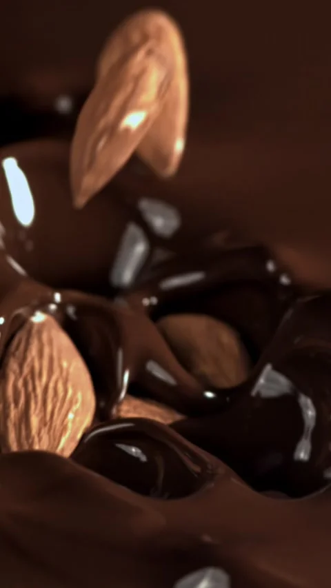 The almonds fall into the melted chocolate. Filmed on a high-speed camera at Stock Footage 335376382