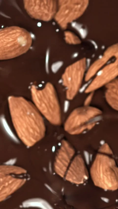 The almonds fall into the melted chocolate. Filmed on a high-speed camera at Stock Footage 335378659