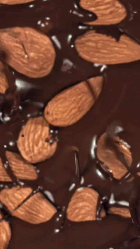 The almonds fall into the melted chocolate. Filmed on a high-speed camera at Stock Footage 335380306