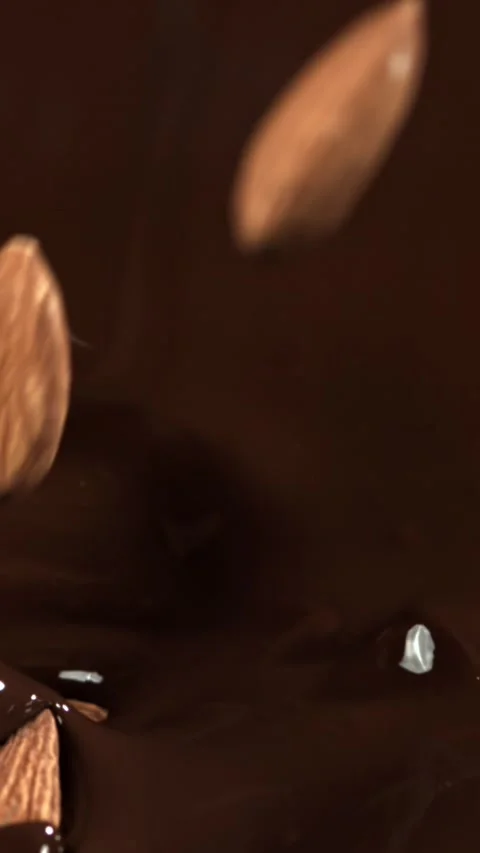 The almonds fall into the melted chocolate. Filmed on a high-speed camera at Stock Footage 335382386