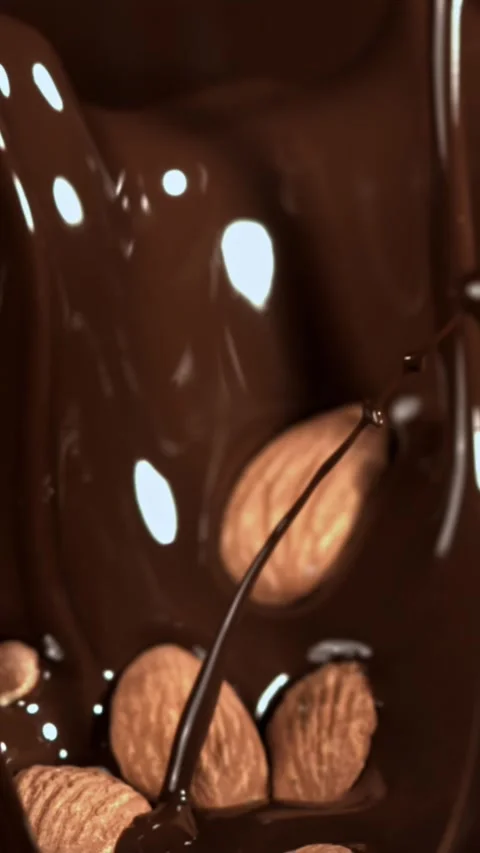 The almonds fall into the melted chocolate. Filmed on a high-speed camera at Stock Footage 335384738