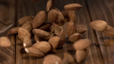 Almonds fall onto a wooden surface in a kitchen during the day with natural Video stock 323147786