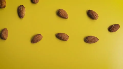Almonds falling from above on a yellow background Vídeos de archivo 188568067