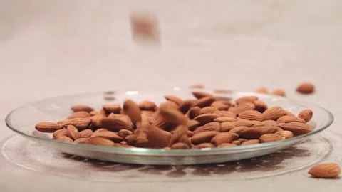 Almonds falling down into glass bowl Stock Footage