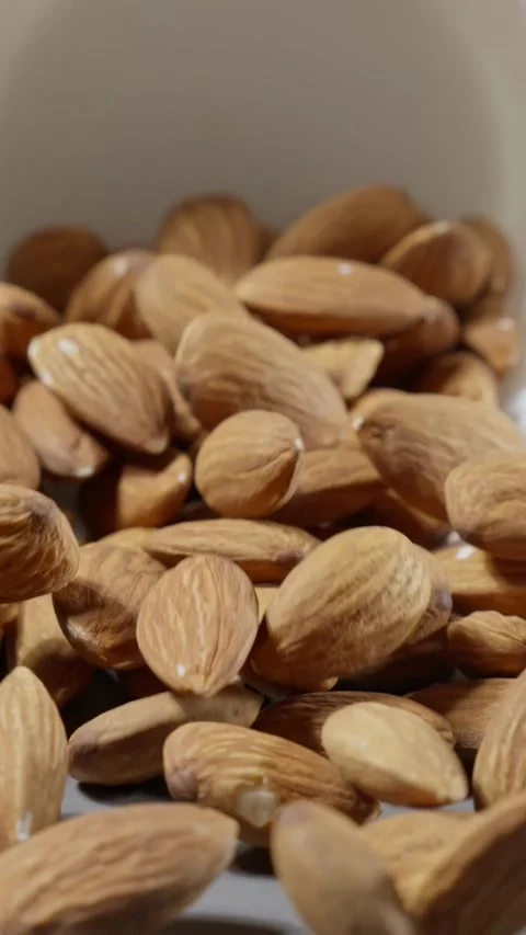 Almonds falling on grey background. Almond nuts fall on table. Brown almond nuts Video stock 297089886