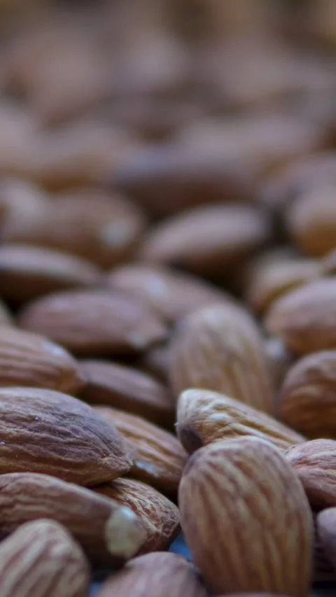Almonds falling on grey background. Almond nuts fall on table. Close-up of brown Video stock 303489714