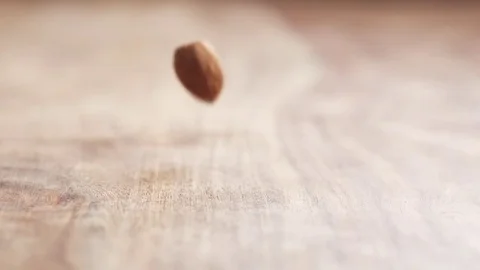 Almonds falling in slow motion on wooden table Stock Footage