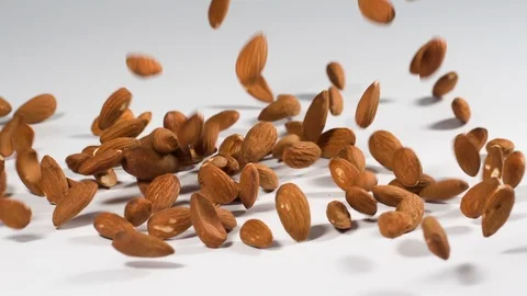 Almonds falling onto a white surface in slow motion Video stock 116645489