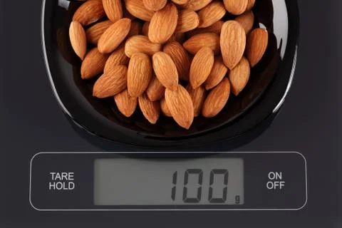 Almonds on kitchen scale Stock Photos