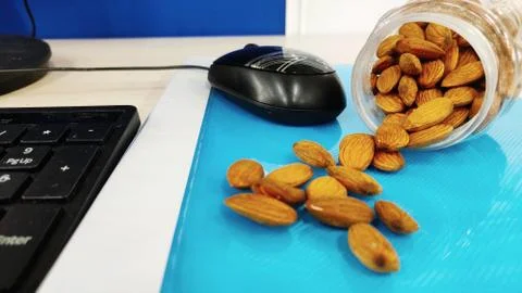 Almonds nut on office Table and in transparent box for healthy snacks diet plan Stock Photos
