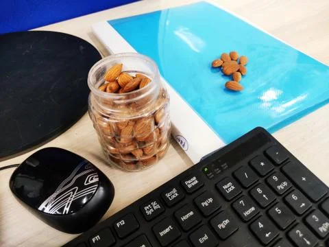 Almonds nut on office Table and in transparent box for healthy snacks diet plan Stock Photos