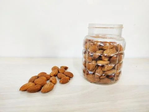 Almonds nut on Table and in transparent box light colour background with space Stock Photos