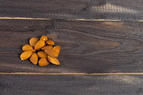 Almonds scattered on a dark table. Copyspace, flatlay on wood background. Stock Photos