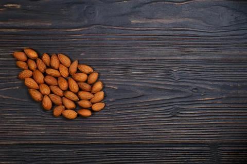 Almonds in the shape of a nut, copy space. Nuts on black wooden background. A Stock Photos