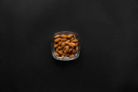 Almonds in a small plate on a black table. Almond is a healthy vegetarian Stock Photos