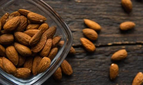Almonds in a small plate with scattered nuts of almonds around a plate on a Stock Photos