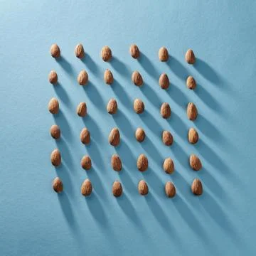 Almonds in a square shape in a blue paper background. Organic food Stock Photos