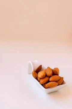 Almonds on a white ceramic spoon on white background. Stock Photos
