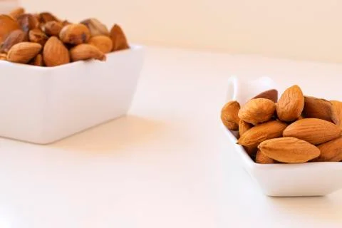 Almonds on a white ceramic spoon on white background. Stock Photos
